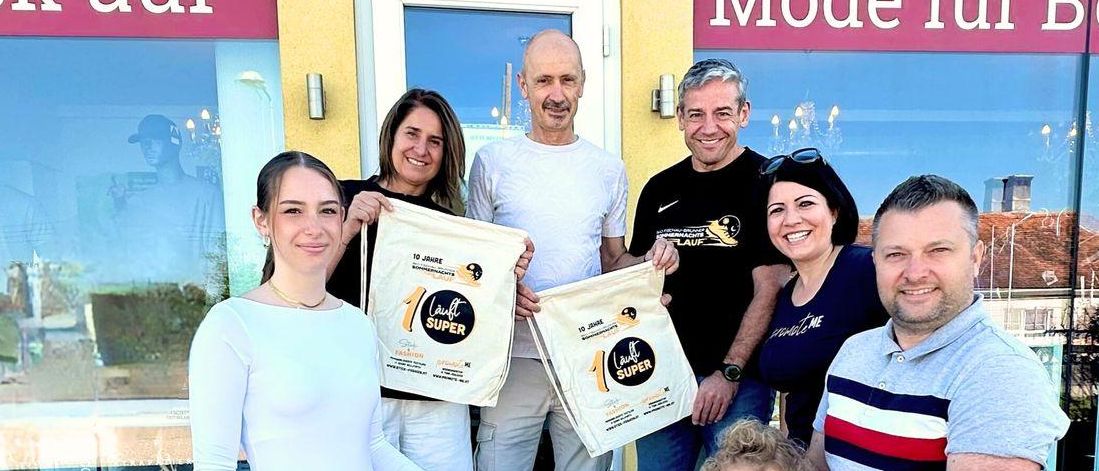 Eine sechsköpfige Familie steht auf den Stufen vor einem Geschäft mit dem Schild 'Stick & fashion & Druck auf' und 'Mode für Beruf'. Sie halten Tüten mit der Aufschrift 'Cool Super'.