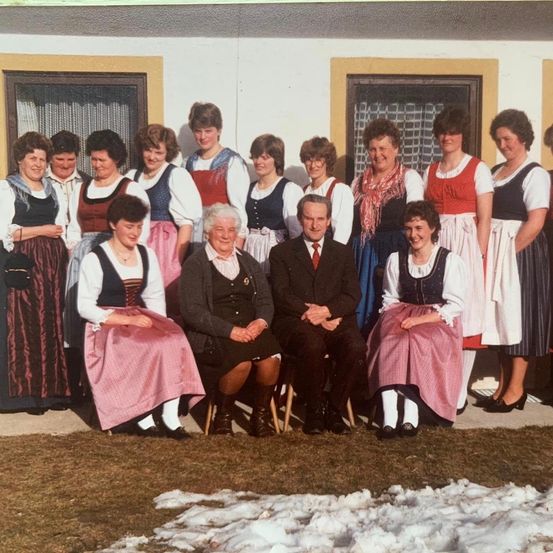 Eine Gruppe von Menschen in traditioneller Kleidung, posiert für ein Foto vor einem Gebäude.
