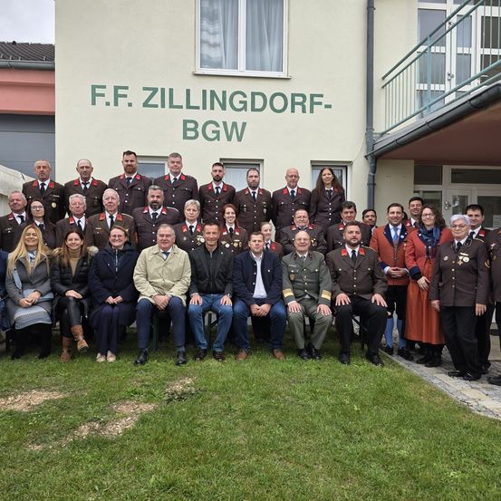 Ein Gruppenfoto von uniformierten und zivilen Personen vor dem F.F. Zillingdorf-BGW-Gebäude.