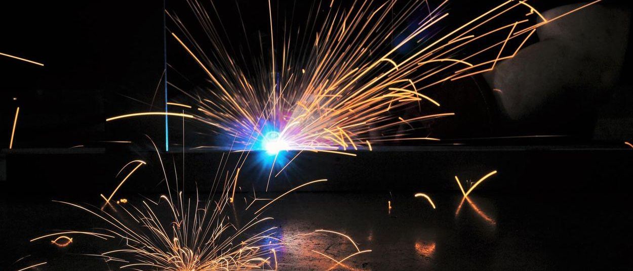 Ein Schweißbrenner stößt helle Funken aus und erzeugt ein blendendes Schauspiel vor einem dunklen Hintergrund.