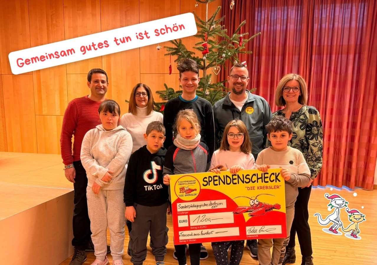 Eine Gruppe von Menschen posiert für ein Foto vor einem Weihnachtsbaum und hält einen großen Scheck mit der Aufschrift 'SPENDENSCHECK' und dem Betrag von 1.200 Euro.