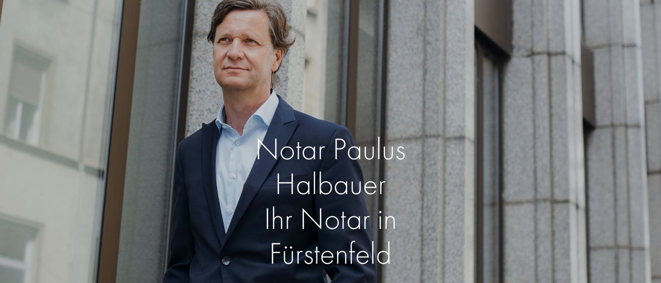 Ein Mann in einem dunkelblauen Anzug steht vor einem Gebäude und lächelt für ein Foto. Der Text lautet 'Notar Paulus Halbauer Ihr Notar in Furstenfeld'.