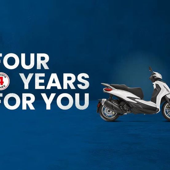 Ein weißer Roller mit blauem Hintergrund zeigt den Text 'Vier Jahre für Sie' und ein Logo mit der Nummer 4.