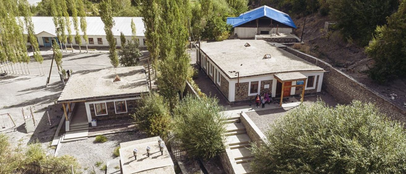 Eine Vogelperspektive einer kleinen Ortschaft mit einem Gebäude, einem blauen Zelt und einer Gruppe von Menschen, die davor stehen.