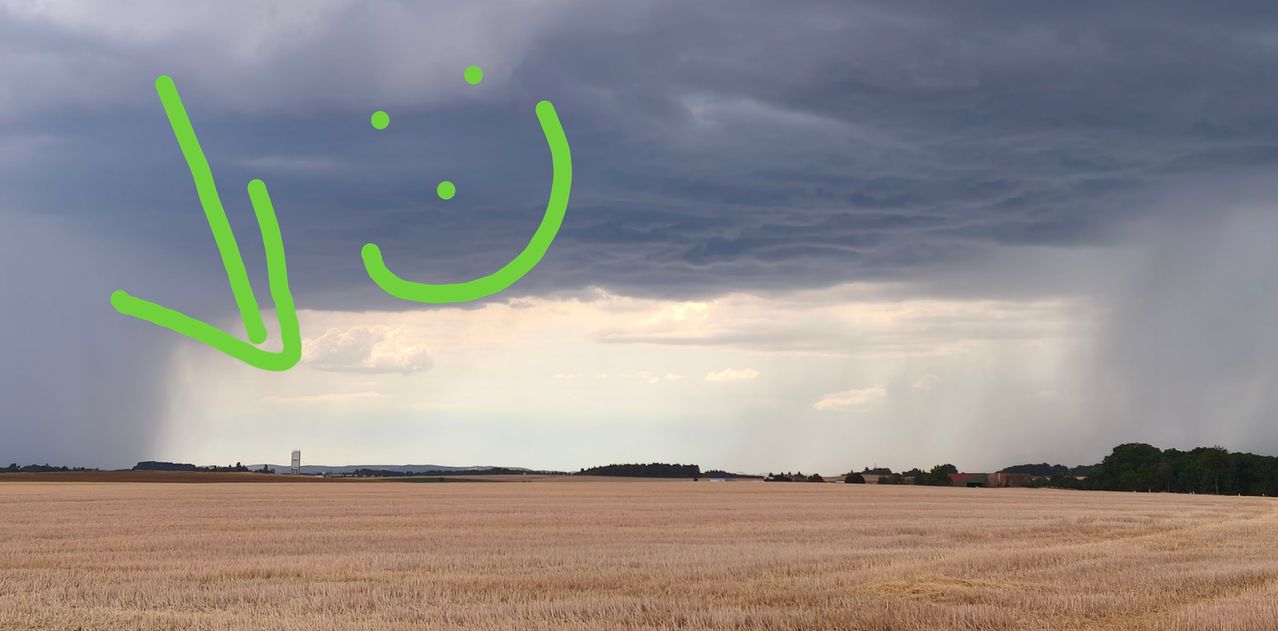 A wide field under a cloudy sky with a green smiley face drawn in the clouds.