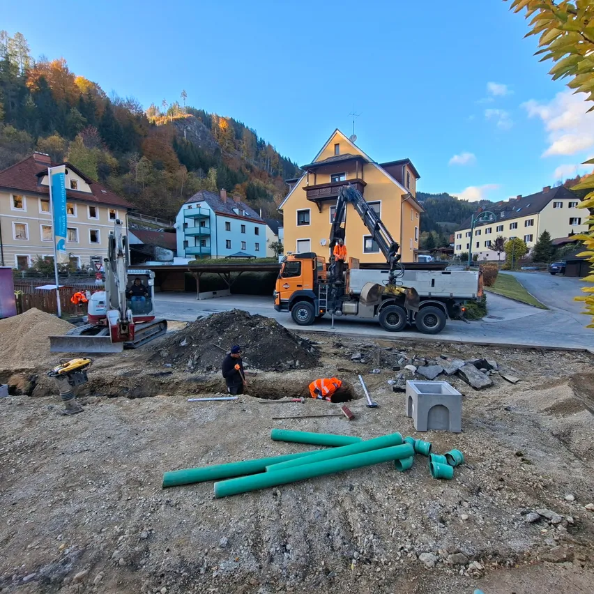 Ein Bauplatz mit Arbeitern, Maschinen und großen Rohren an einem sonnigen Tag.