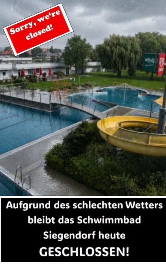 A swimming pool with a yellow slide and a closed sign on top. The pool is surrounded by a metal fence.