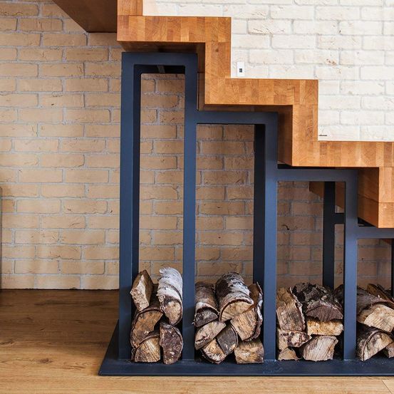 Eine Holztreppe mit Stufen, die zu einem Kamin mit einer Ziegelmauer und Holzscheiten führen, die in einem Metallständer gestapelt sind.
