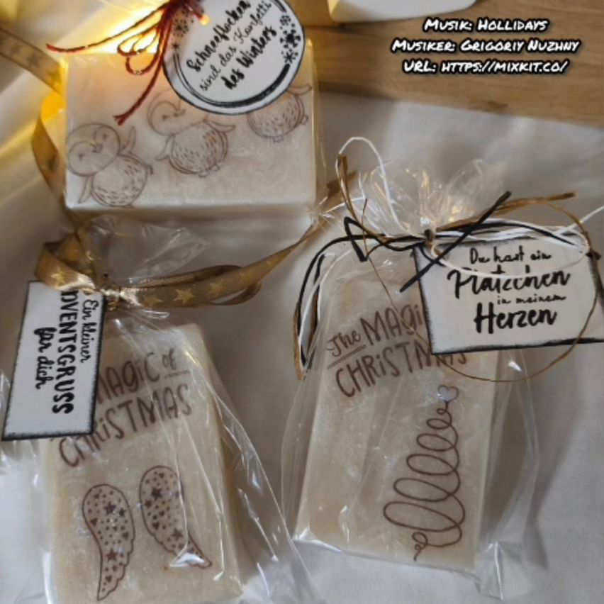 Drei Weihnachtsseifen in Plastikverpackung mit Schleifen. Jede hat ein Etikett mit dem Text 'Die Magie von Weihnachten'. Ein kleines Etikett auf der obersten Seife lautet 'Magie von Weihnachten'.