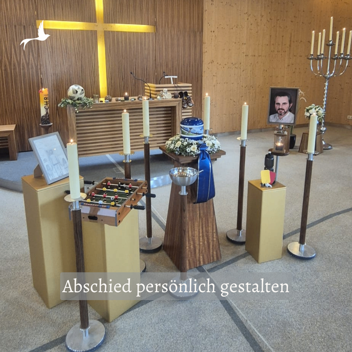 Ein Gedenkaltar mit Kerzen, Blumen und einem Porträt eines Mannes. Der Altar hat ein Kreuz, einen Fußball und einen Tischkicker. Der Text lautet 'Abschied persönlich gestalten'.