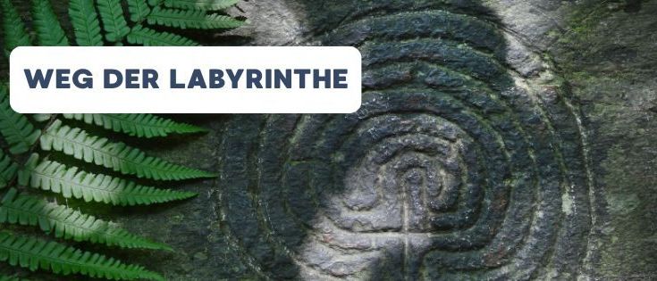 Ein steinernes Labyrinth mit einem Spiraldesign und den Worten 'Weg der Labyrinthe' auf weißem Hintergrund, umgeben von grünen Blättern.
