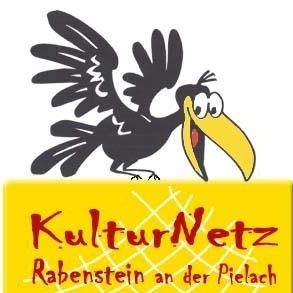 Ein schwarzer Vogel mit einem gelben Schnabel hockt auf einem gelben Schild. Das Schild zeigt in roten Buchstaben mit weißer Kontur KulturNetz Rabenstein an der Pielach. Darunter steht in kleineren Buchstaben Musik, Theater, Literatur.