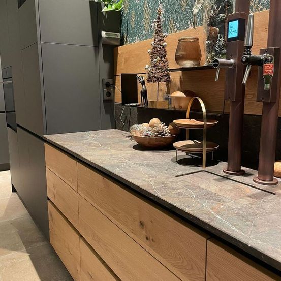 Eine moderne Küche mit Granitarbeitsplatte, Holzschränken und einem Regal, das einen Weihnachtsbaum, Gläser und andere Dekorationsartikel enthält.