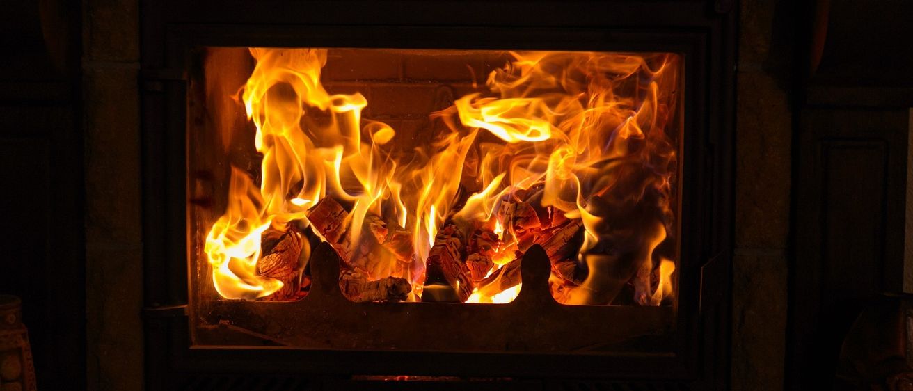 Ein Kamin mit einem hellen, warmen Feuer im Inneren, das ein warmes Licht auf die Ziegelwände wirft.