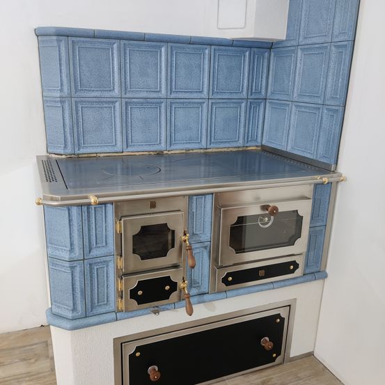 Eine moderne Küche mit einer blauen Fliesenrückwand und einem Edelstahlofen mit zwei Öfen. Der Ofen hat eine schwarze und silberne Oberfläche mit Holzgriffen.