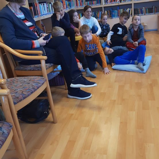 Bild enthält, Floor, Flooring, Wood, Book, Library, Couch, Furniture, Living Room, Interior Design, People