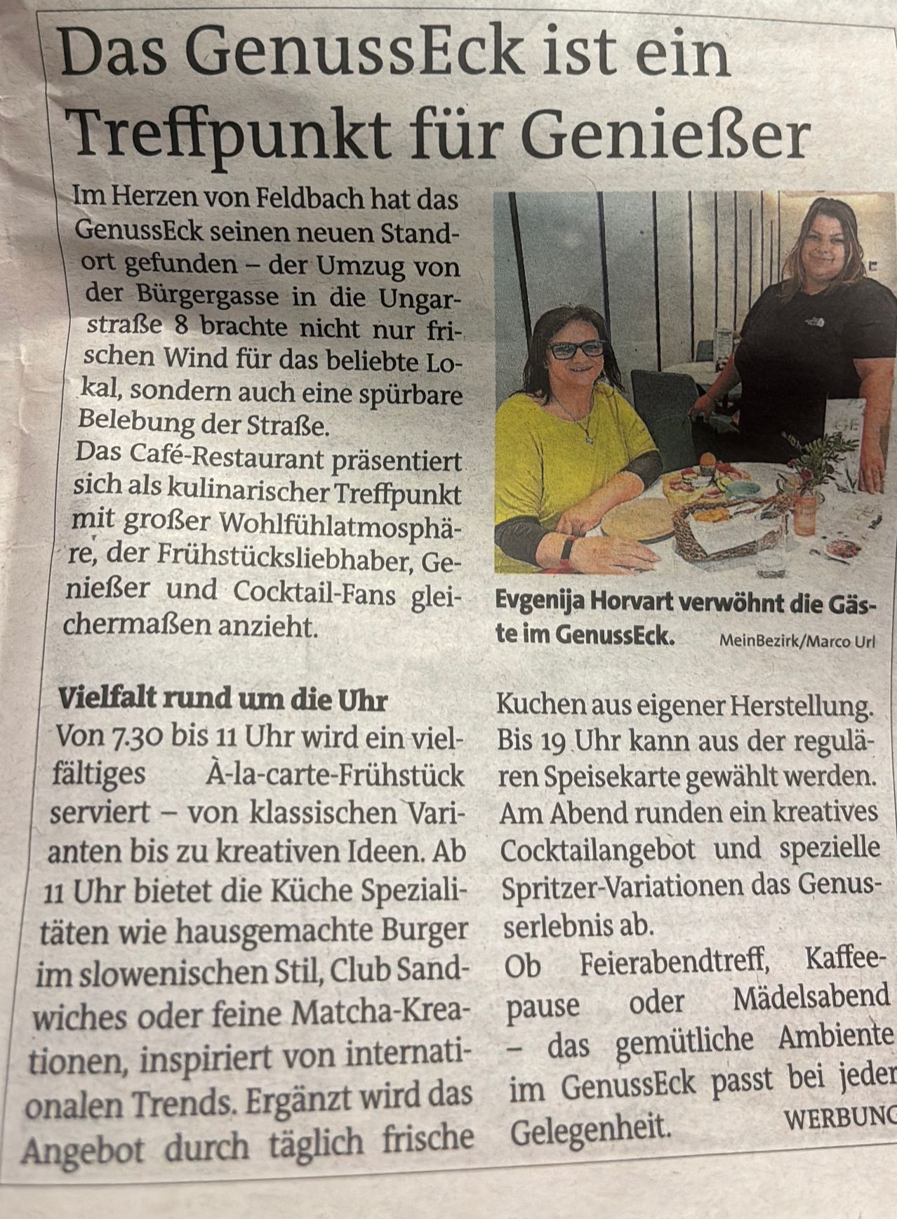 Ein Artikel über GenussEck, ein Café-Restaurant in Feldbach, zeigt zwei Frauen, Evgenija Horvart und eine andere, die lächelnd sitzen. Der Text beschreibt die Vielfalt der Frühstücks- und Abendessenoptionen im GenussEck.