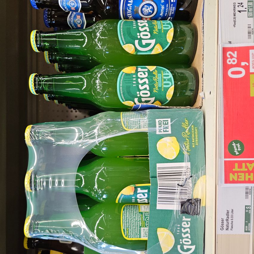 A shelf with several bottles of Gosser lemonade stacked on top of each other. The bottles are green with yellow caps and lemon images. A transparent plastic bag is in front of the bottles.