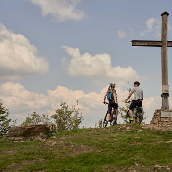Bild enthält, Cross, Symbol, Helmet, Person, Tree, Bicycle, Vehicle, Fir, Outdoors