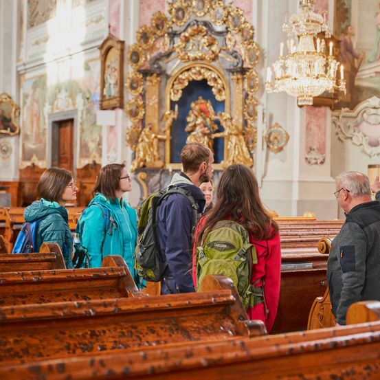 Bild enthält, Prayer, Adult, Male, Man, Person, Indoors, Chandelier, Female, Woman, Backpack