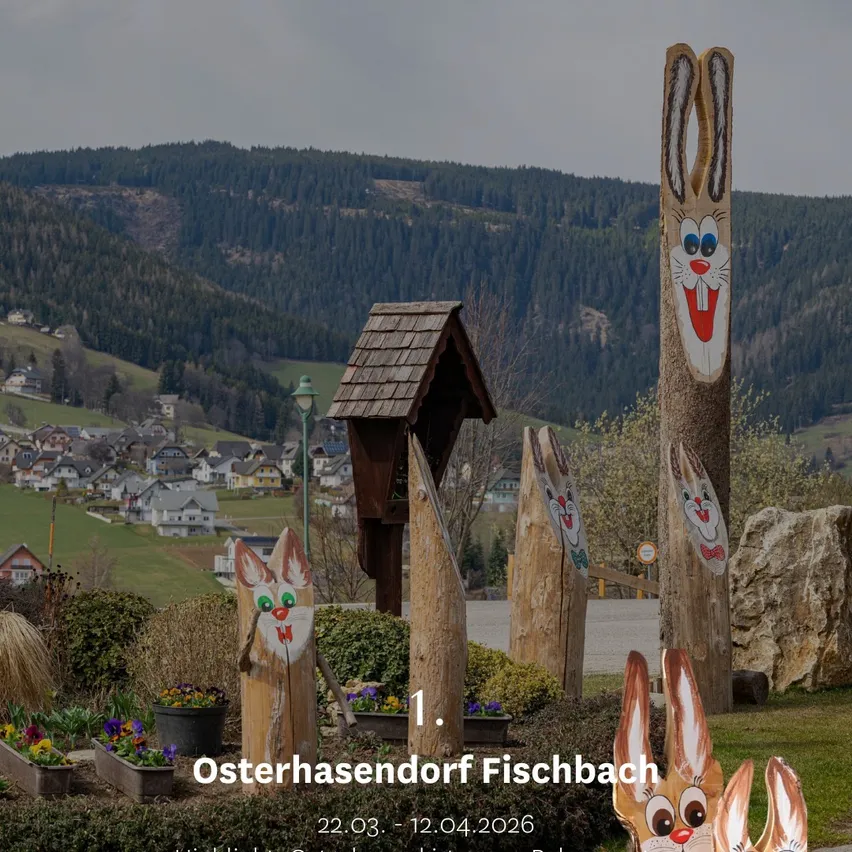 Osterhasendorf Fischbach in Österreich, vom 22.03. bis 12.04.2026. Eine Landschaft mit Bergen, Häusern und Osterhasen auf Pfählen.