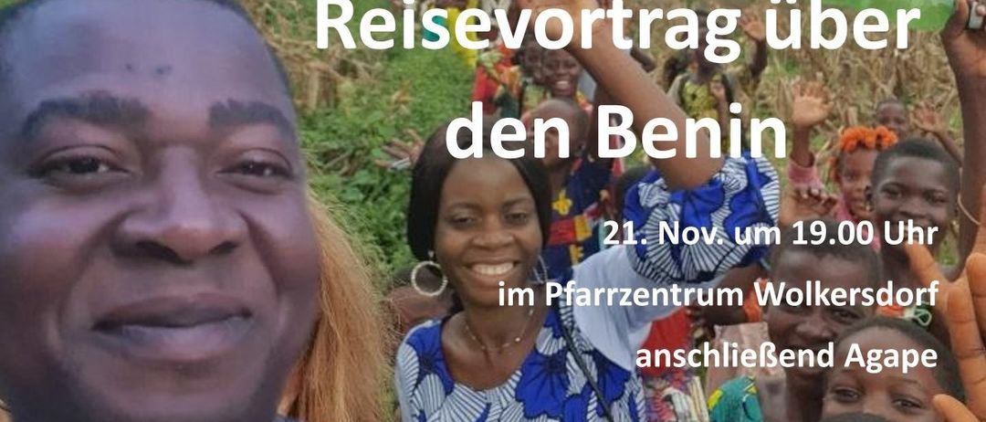 Eine lächelnde afrikanische Frau spricht vor einer Menge mit einem Mann hinter ihr, der seine Hand hochhält. Der Text im Bild lautet 'Reisevortrag in den Benin' und das Datum '21. Nov. um 1'.