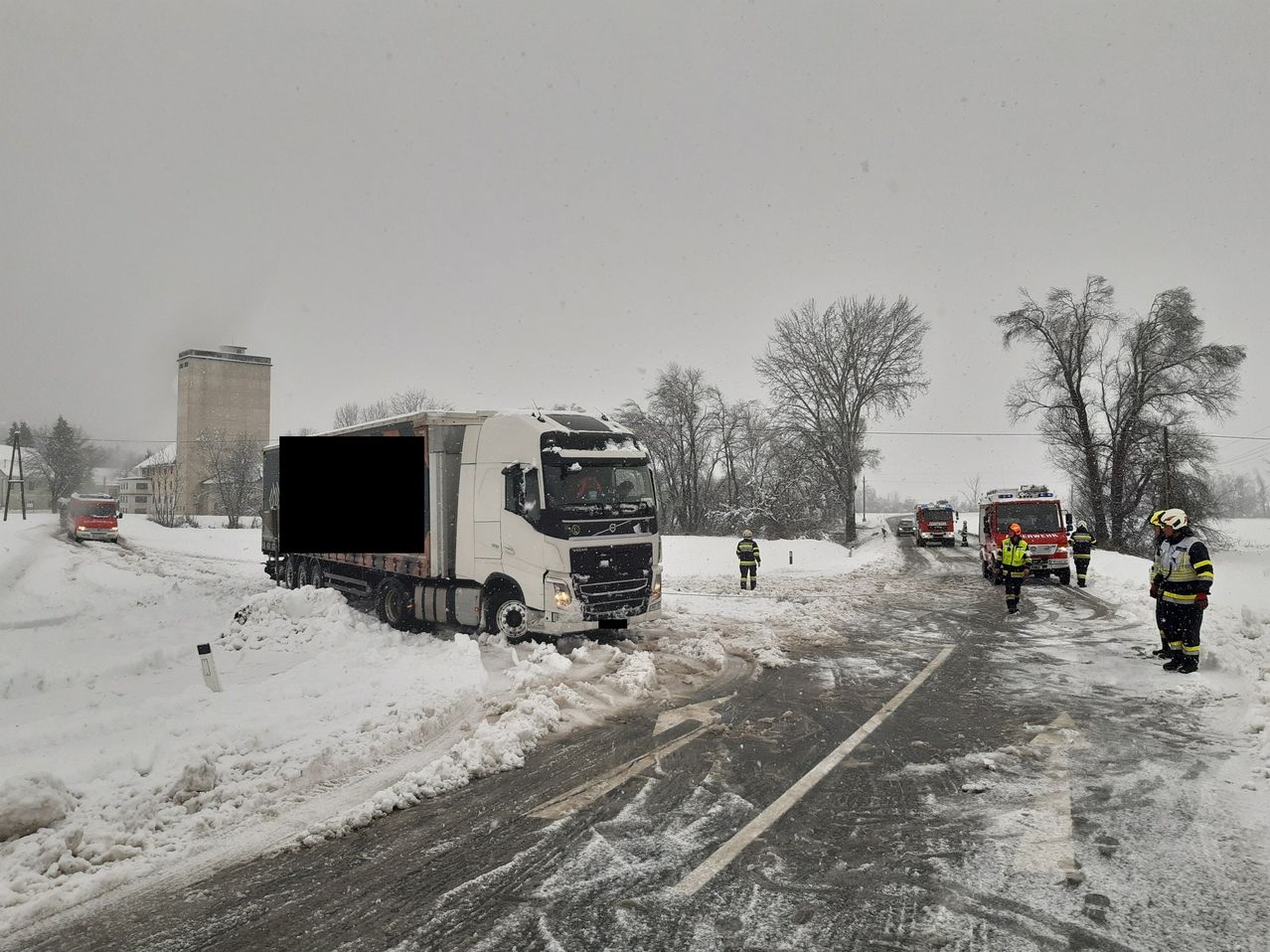 Ein weißer Lkw ist im Schnee stecken geblieben. Rettungskräfte sind vor Ort.