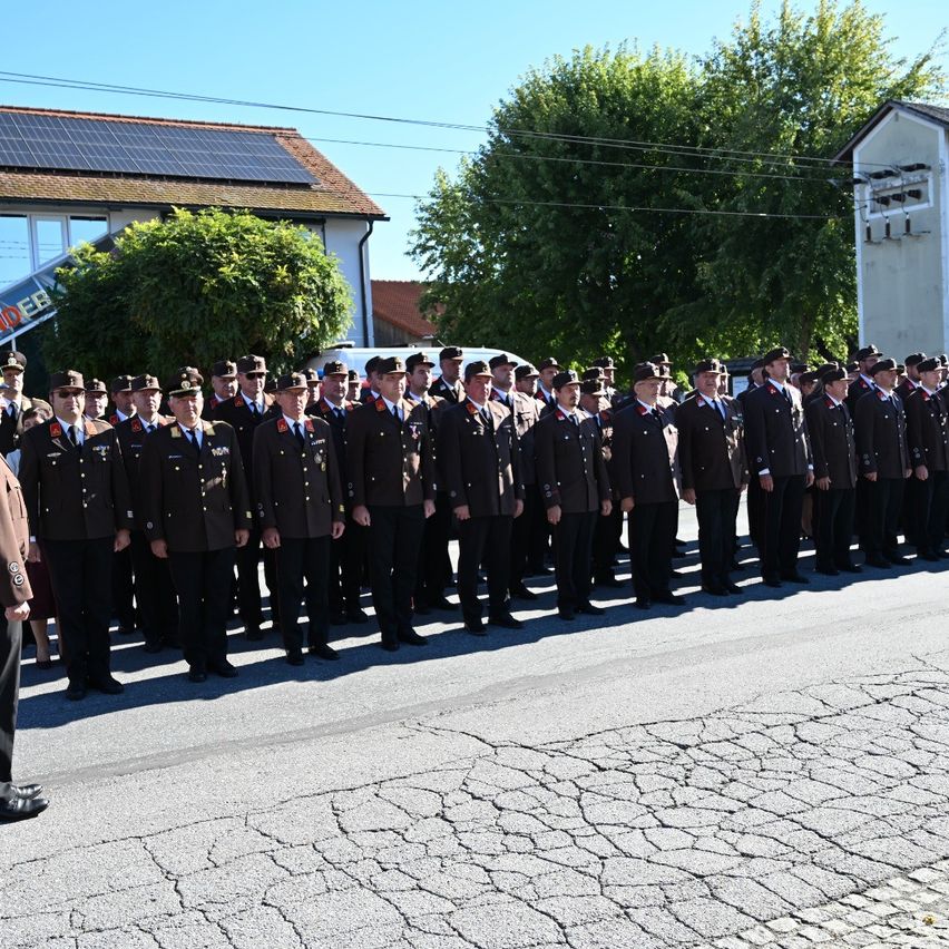 Eine Gruppe uniformierter Personen, wahrscheinlich eine militärische oder polizeiliche Einheit, steht in Formation auf einer Straße.