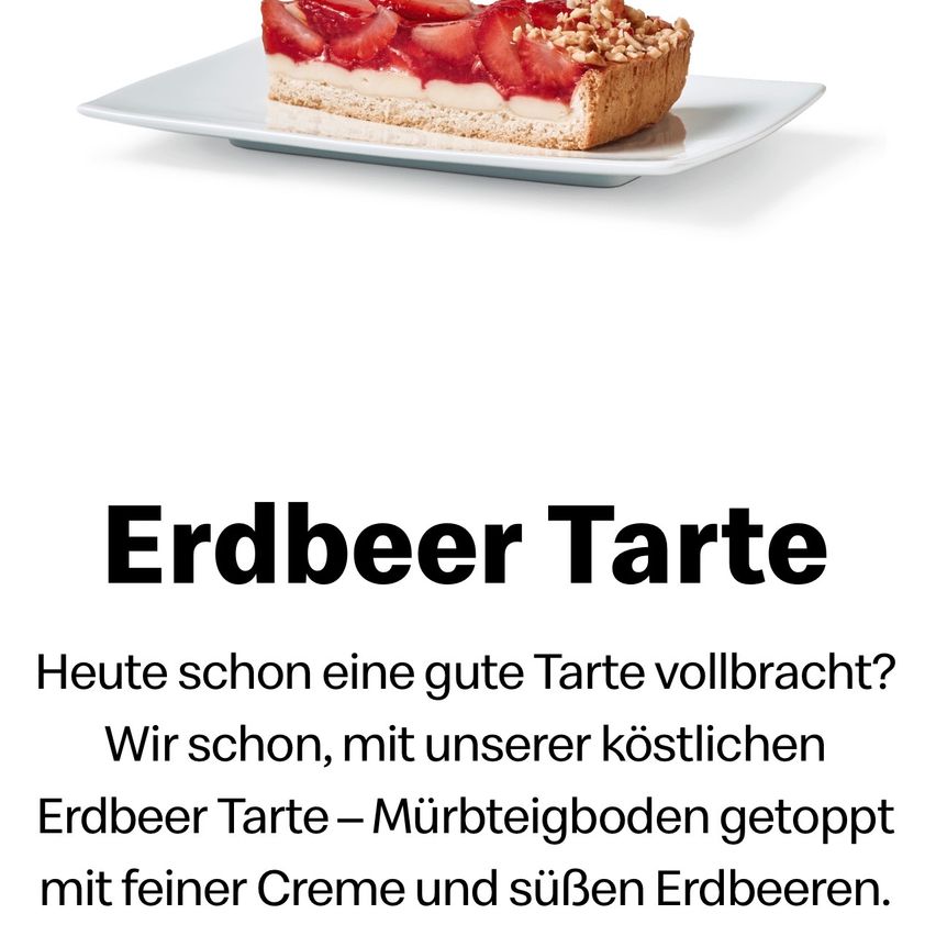 Eine Scheibe Erdbeertarte befindet sich auf einem weißen Teller. Sie besteht aus einem Mürbeteigboden, einer cremigen Füllung und frischen Erdbeeren. Die Tarte steht auf einer weißen Oberfläche.