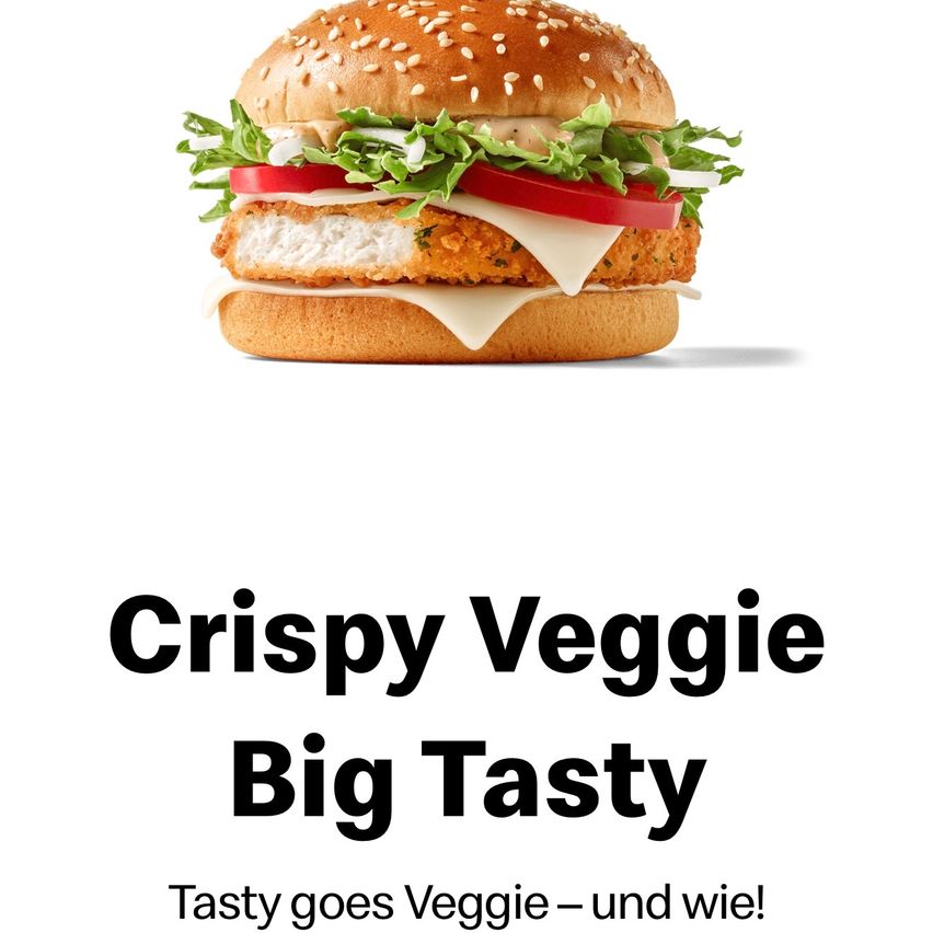A close-up of a Crispy Veggie Big Tasty burger with a sesame seed bun, lettuce, tomato, and a crispy veggie patty. The burger is topped with melted cheese.