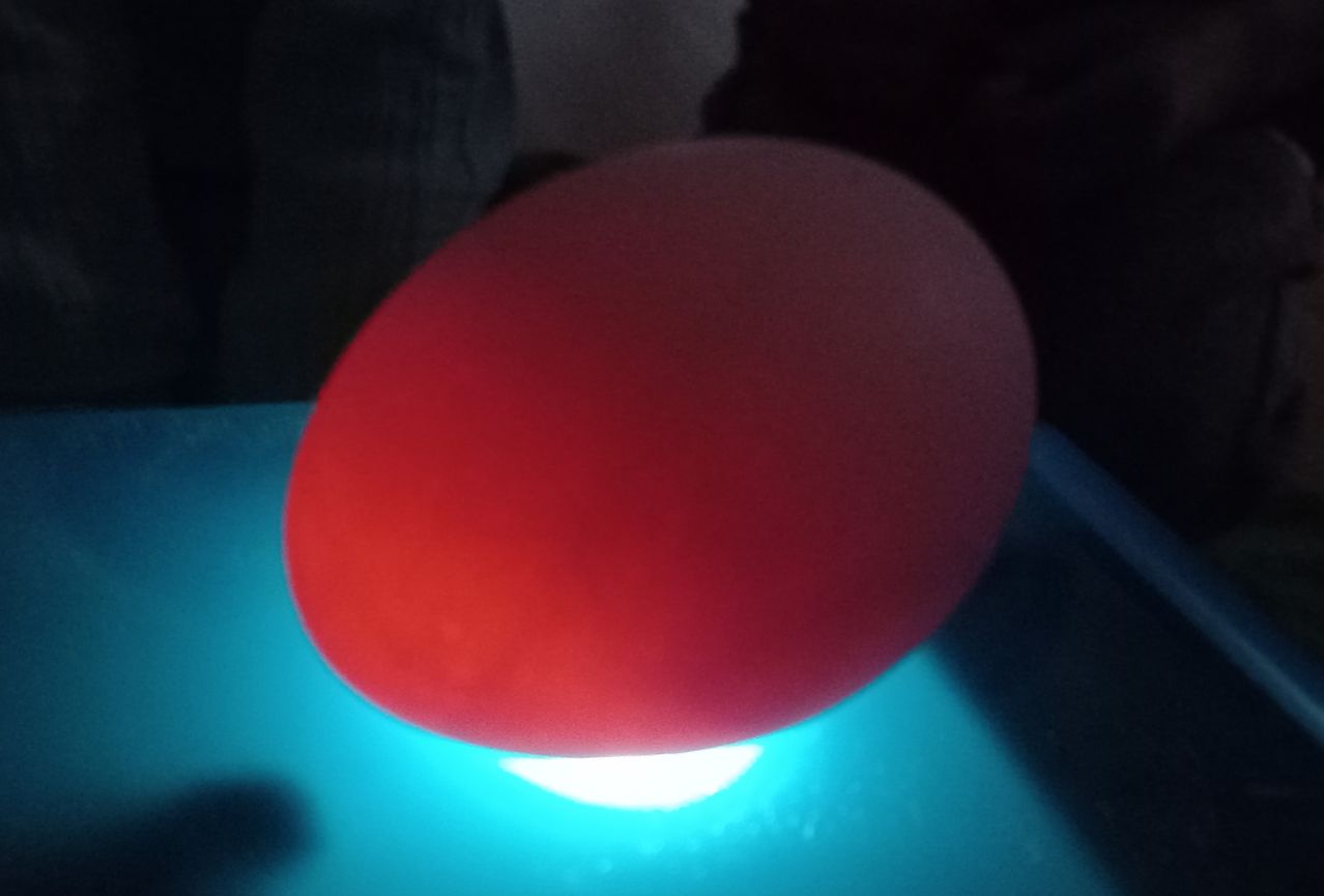 Eine leuchtend rote Kugel wird von unten von einem blauen Licht beleuchtet, möglicherweise in einem dunklen Raum.