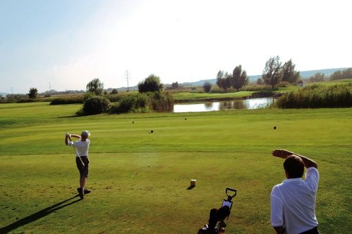 Zwei Männer spielen Golf auf einem Golfplatz. Ein Mann schwingt den Golfschläger.