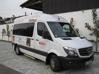 Ein weißer Mercedes-Benz Sprinter-Van mit 'SPAR' und Werbeinhalten an der Seite ist vor einem Gebäude geparkt.