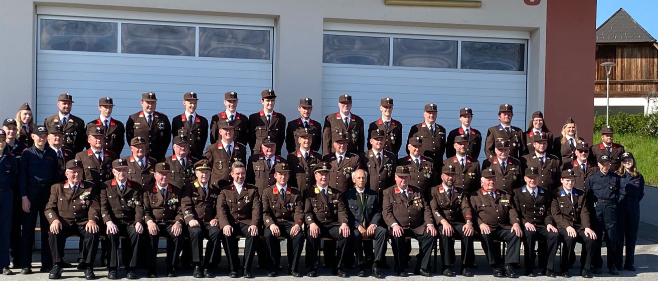 Eine Gruppe von Feuerwehrleuten in Uniform posiert für ein Foto vor dem W. Feuerwehr Schamberg-Gebäude.