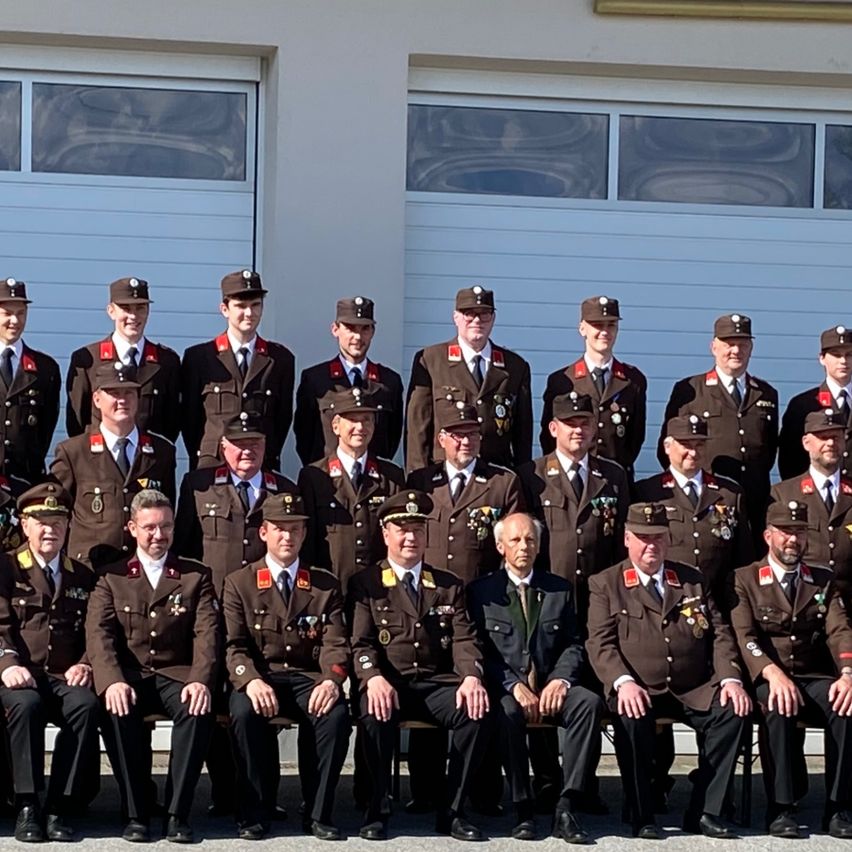 Eine Gruppe von Feuerwehrleuten in Uniform posiert für ein Foto vor dem W. Feuerwehr Schamberg-Gebäude.