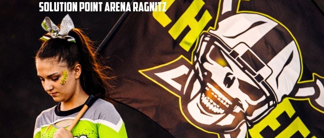 Spieltag-Eventposter. Es zeigt eine Frau in einer Cheerleader-Uniform, die eine Flagge hält. Das Poster ist schwarz und gelb mit Text in weiß. Der Termin ist am 19. April, Beginn um 14 Uhr. Ort: Solution Point Arena Ragnit. Teams: Reaver vs. Blue Hawks.