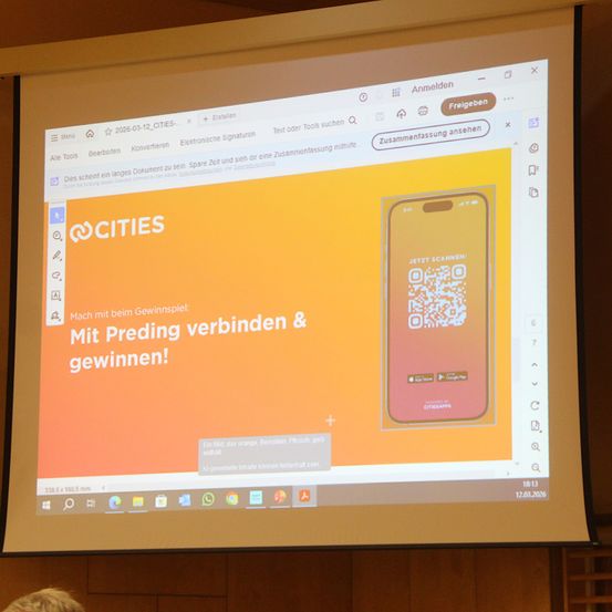Ein Bildschirm zeigt eine Webseite für eine Cities-App mit orangefarbenem Hintergrund und einem Telefon mit QR-Code. Der Text lautet 'Verbinde dich mit Preding und gewinne!' Das Datum ist der 3. Dezember 2020.