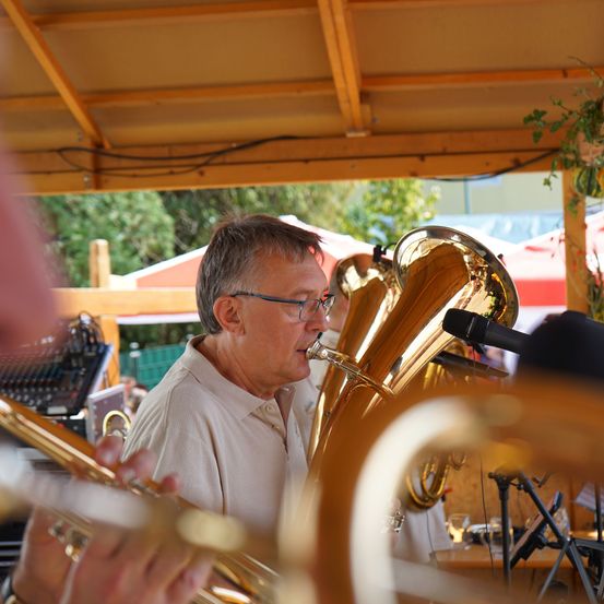 Ein Mann mit Brille spielt eine Tuba unter einem Baldachin mit einem Mikrofon vor ihm.