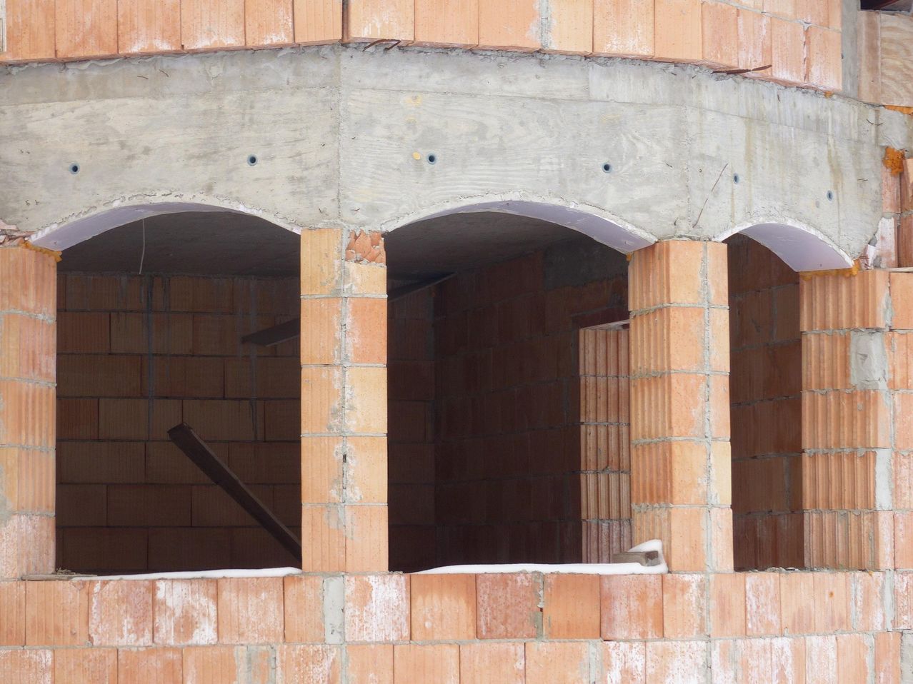 An image of a construction site with brick walls and concrete supports, showing the structural framework.