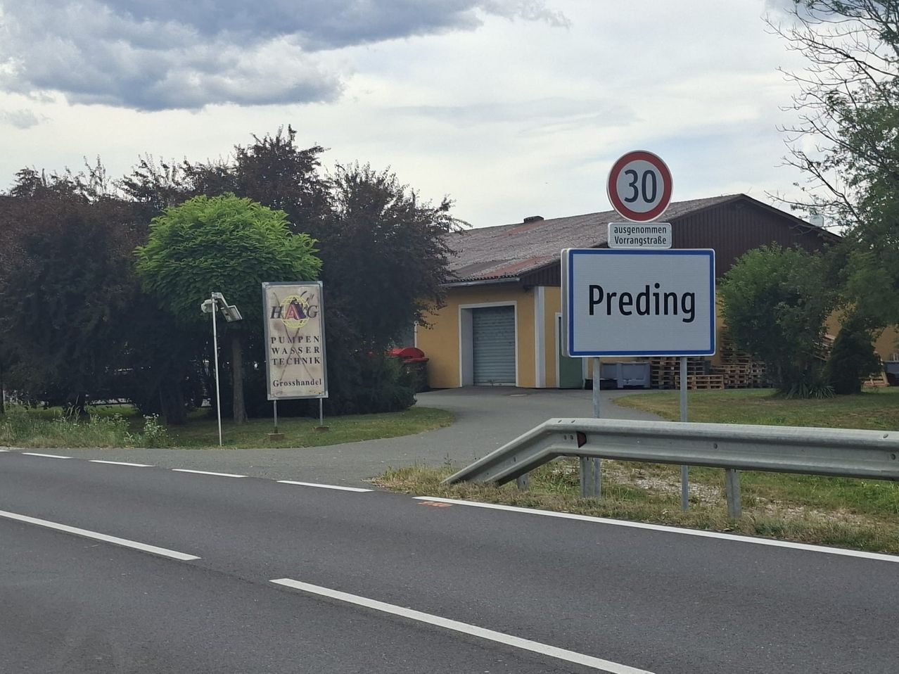 A road sign indicates Preding and a speed limit of 30 km/h. A yellow building with a garage and a sign for Pumpen Wasser Technik is visible.