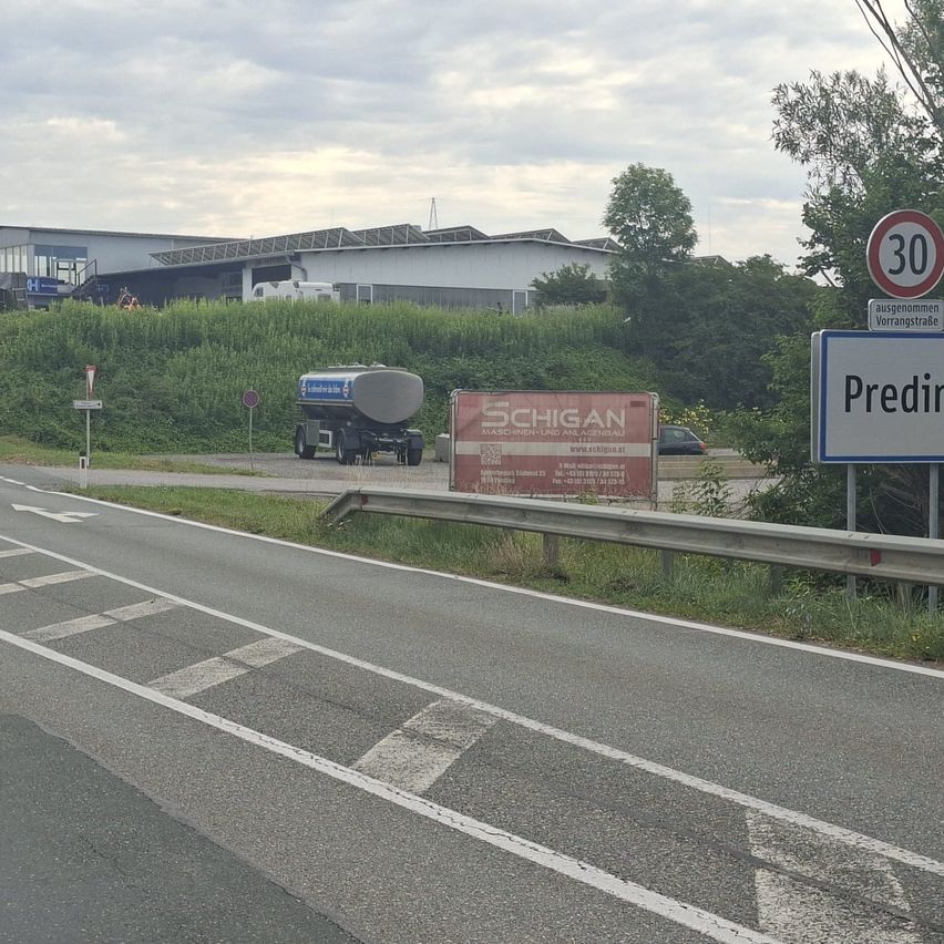 A highway with a Schigan sign and a tanker truck. A '30' speed limit sign is present, and there is a bush in the background.