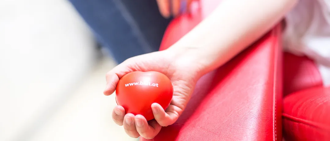 Eine Person hält einen roten Ball in der Hand, auf dem die Website www.bist.at gedruckt ist.