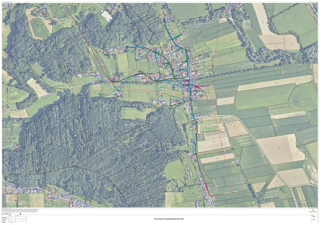 Luftaufnahme eines ländlichen Gebiets mit grünen Feldern und Bäumen. Ein Netz aus Straßen und Wegen verbindet verschiedene Bereiche. Gebäude und Strukturen sind über die Landschaft verstreut. Das Bild enthält eine farbcodierte Legende.
