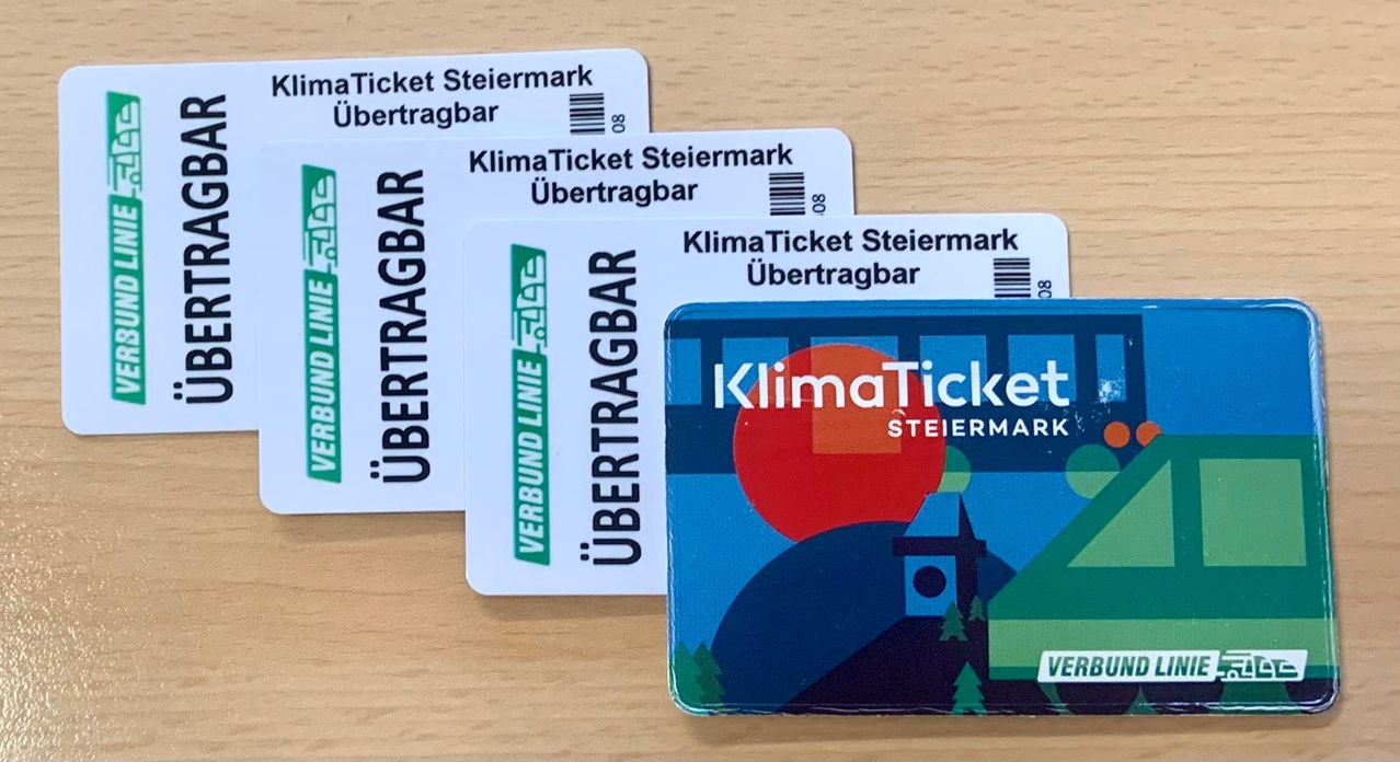 Drei KlimaTicket Steiermark-Karten liegen auf einer Holzoberfläche. Eine hat einen blauen Rand, die anderen sind weiß.