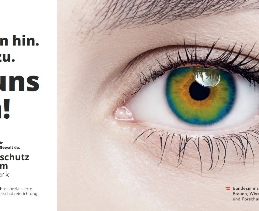 Ein Nahaufnahme eines weiblichen Auges mit einer hellen, lebhaften Iris, die Grün-, Gelb- und Blautöne zeigt. Die Wimpern sind lang und dick und rahmen das Auge ein. Der Text 'hin.' und 'ns' ist teilweise auf der linken Seite des Bildes sichtbar.