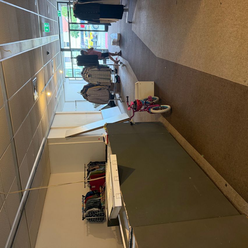 A top-down view of a clothing store with a red bicycle on the floor and a person arranging clothes on a rack.