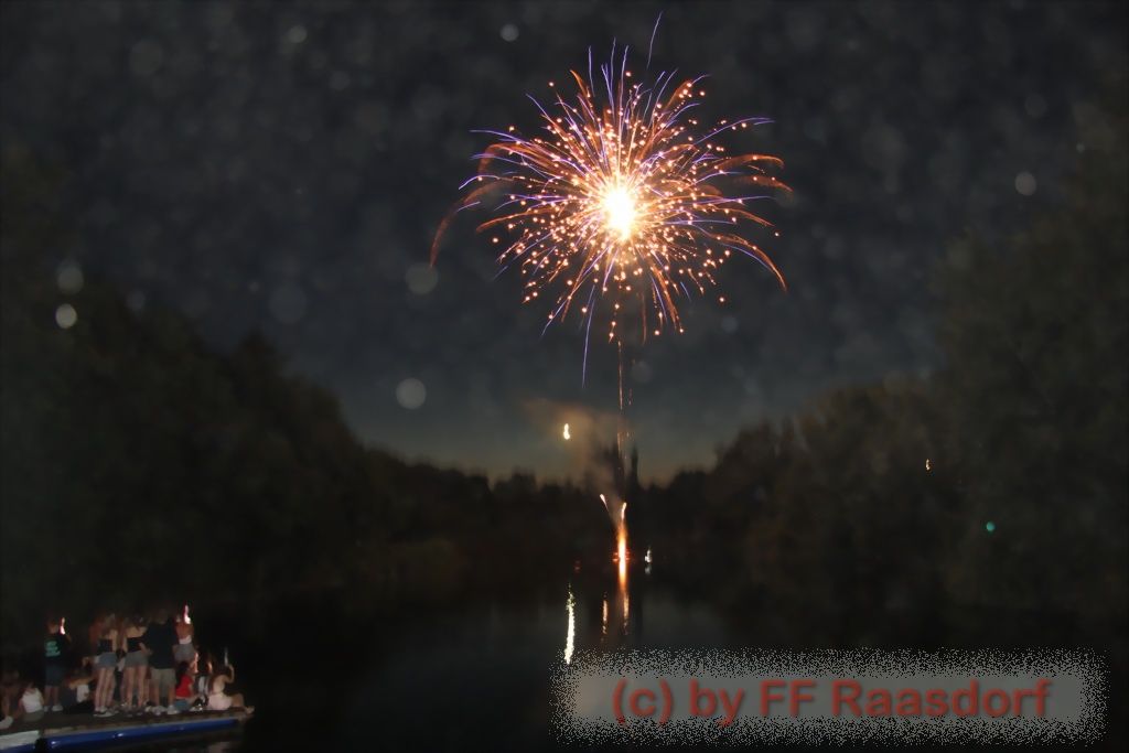 A nighttime fireworks display over a lake, captured by FF Raasdorp.