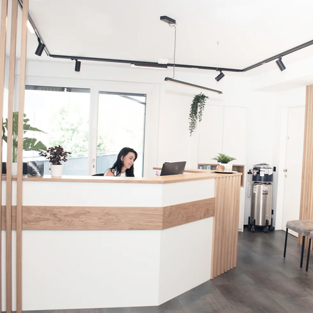 Bild enthält, Reception, Furniture, Table, Person, Indoors, Interior Design, Chair, Plant, Foyer, Laptop