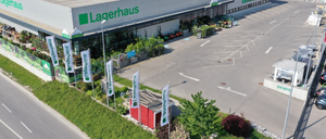 Eine Luftaufnahme des Lagerhaus-Geschäfts mit Bannern, einem roten Schuppen und einem Parkplatz.