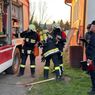 Feuerwehrleute bereiten ihre Ausrüstung in der Nähe eines Feuerwehrwagens vor. Einer überprüft die Sauerstoffflaschen, während ein anderer sich beugt. Beamte beobachten in der Nähe.